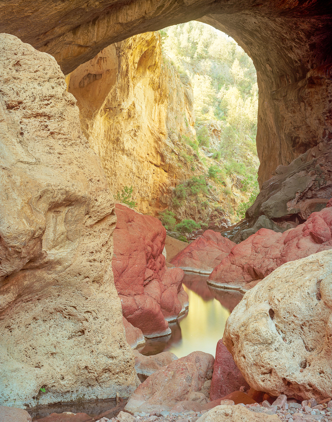 Large blocks of travertine fallen from above frame this view out the downstream end of Tonto Natural Bridge.  The contact between the Haigler Rhyolite and the travertine is visible on the right above the plunge pool.